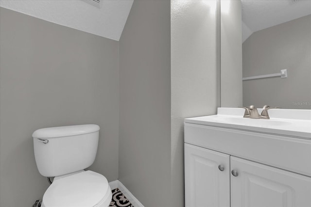 bathroom featuring toilet, vanity, and lofted ceiling