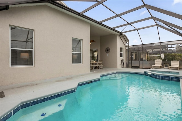 view of pool with glass enclosure, an in ground hot tub, and a patio