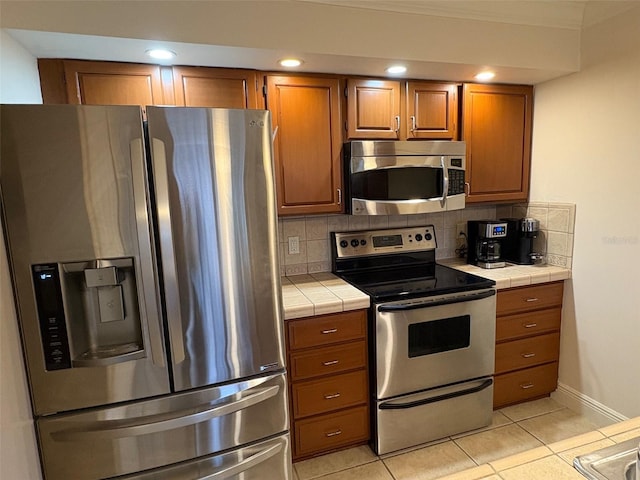 kitchen featuring tasteful backsplash, stainless steel appliances, tile countertops, and light tile patterned floors