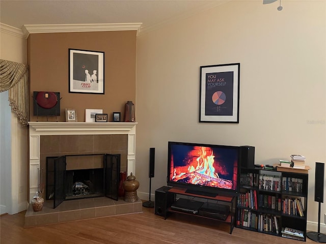 living area featuring a tiled fireplace, hardwood / wood-style floors, and ornamental molding