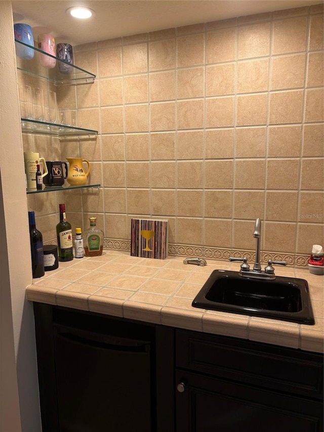 bar featuring sink, backsplash, and tile counters