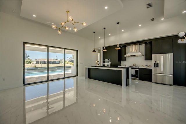 kitchen with pendant lighting, wall chimney exhaust hood, backsplash, stainless steel fridge with ice dispenser, and a center island with sink