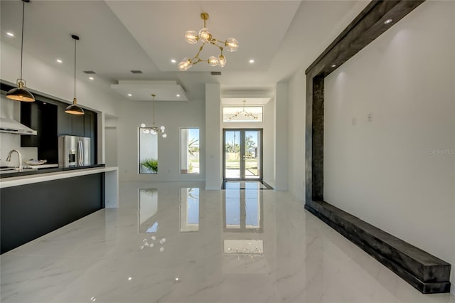 kitchen with french doors, sink, hanging light fixtures, stainless steel fridge, and a chandelier