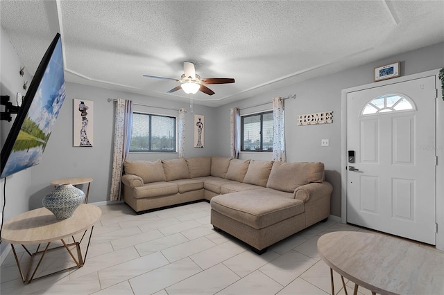 living room with ceiling fan, a textured ceiling, and a wealth of natural light