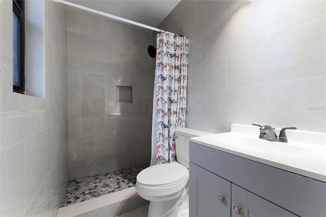 bathroom with vanity, toilet, curtained shower, and tile walls