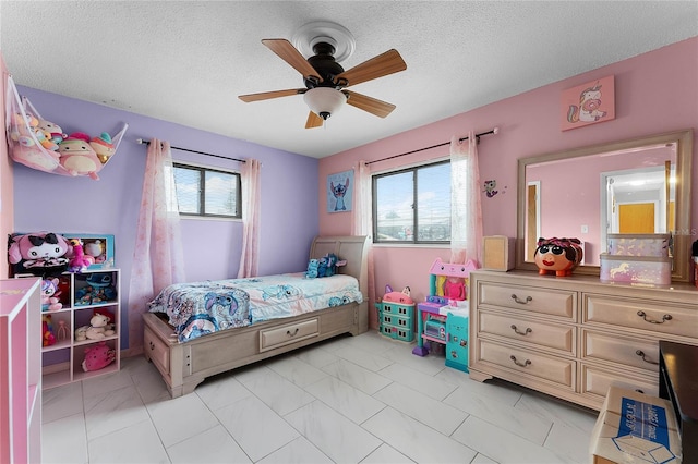 bedroom with ceiling fan and a textured ceiling