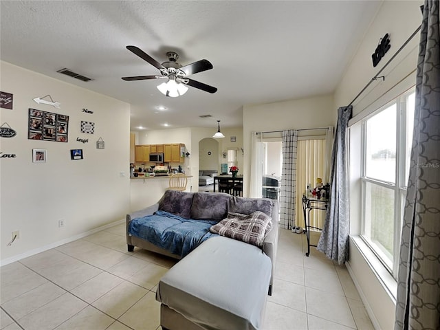 tiled living room featuring a textured ceiling, ceiling fan, and a healthy amount of sunlight