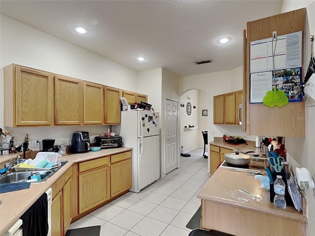 kitchen featuring light brown cabinetry, sink, white fridge, and light tile patterned flooring