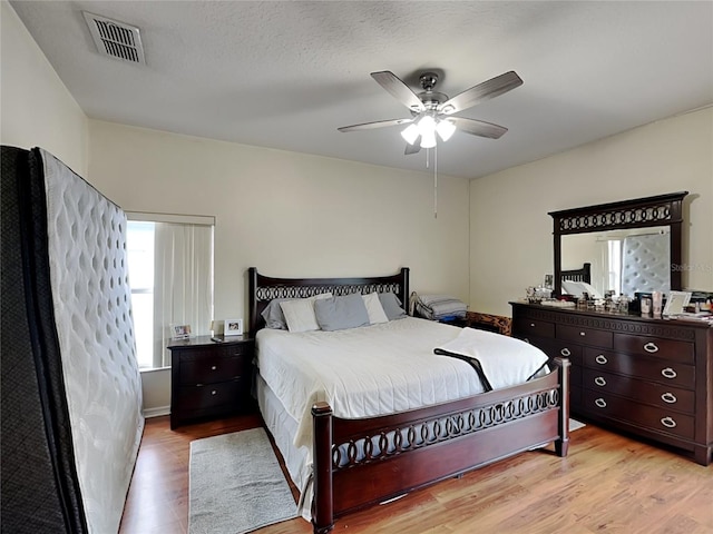 bedroom featuring ceiling fan, light hardwood / wood-style floors, and a textured ceiling