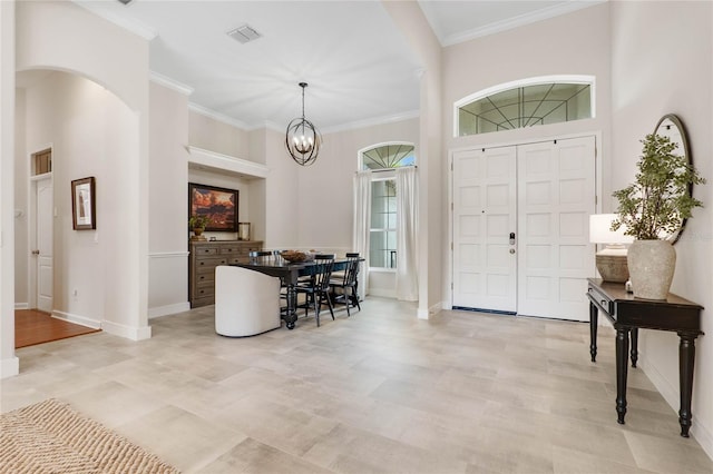 foyer with a high ceiling, ornamental molding, and an inviting chandelier