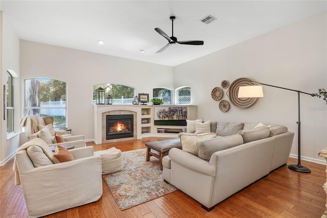 living room with ceiling fan, light wood-type flooring, and a fireplace