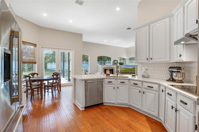 kitchen with kitchen peninsula, tasteful backsplash, dishwasher, white cabinets, and light hardwood / wood-style flooring