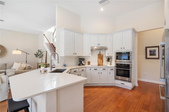 kitchen with light hardwood / wood-style floors, sink, white cabinets, and kitchen peninsula