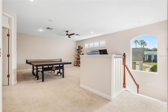 recreation room with ceiling fan and light carpet