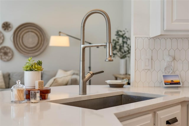 interior details with decorative backsplash, sink, and white cabinets