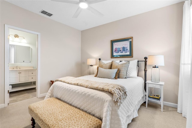 bedroom featuring ceiling fan, light colored carpet, and ensuite bath