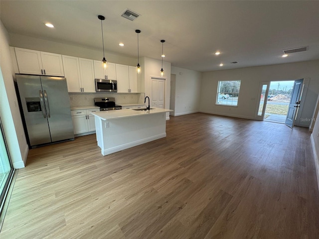 kitchen with pendant lighting, sink, white cabinetry, a kitchen island with sink, and stainless steel appliances