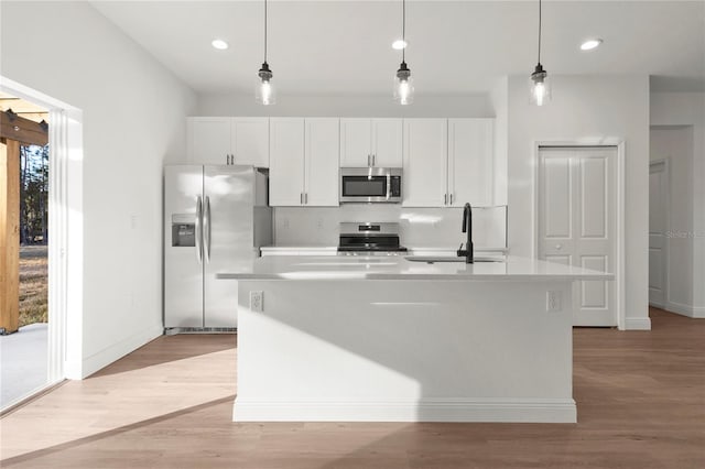 kitchen with pendant lighting, stainless steel appliances, sink, and a center island with sink