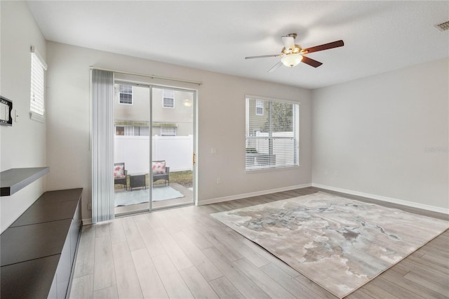 spare room with a wealth of natural light, ceiling fan, and light wood-type flooring