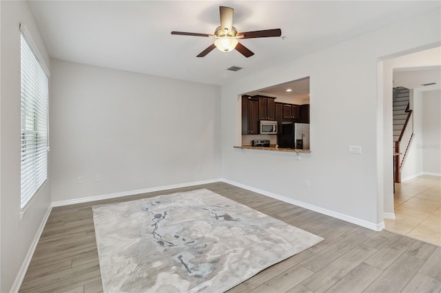 empty room with ceiling fan and light hardwood / wood-style flooring