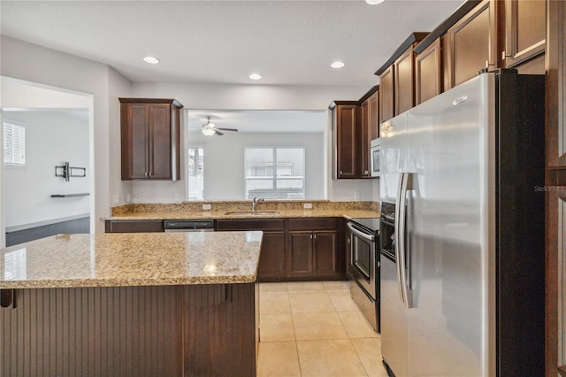 kitchen featuring light tile patterned flooring, appliances with stainless steel finishes, sink, a center island, and light stone countertops