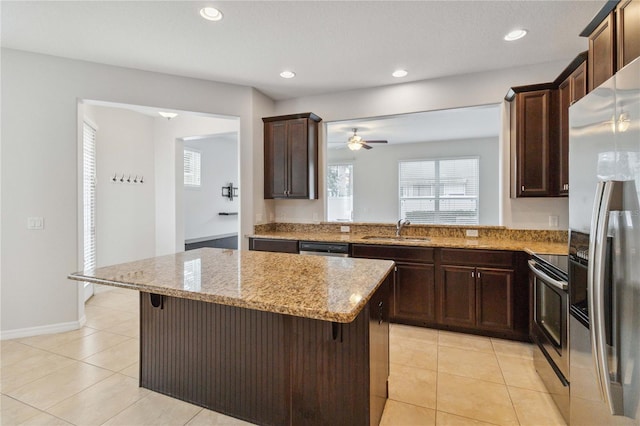 kitchen featuring a kitchen island, appliances with stainless steel finishes, sink, a kitchen breakfast bar, and light stone counters