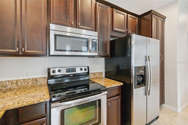 kitchen with stainless steel appliances, light stone countertops, and light tile patterned floors