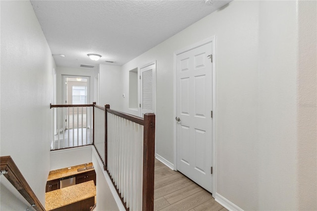 corridor featuring light hardwood / wood-style floors and a textured ceiling