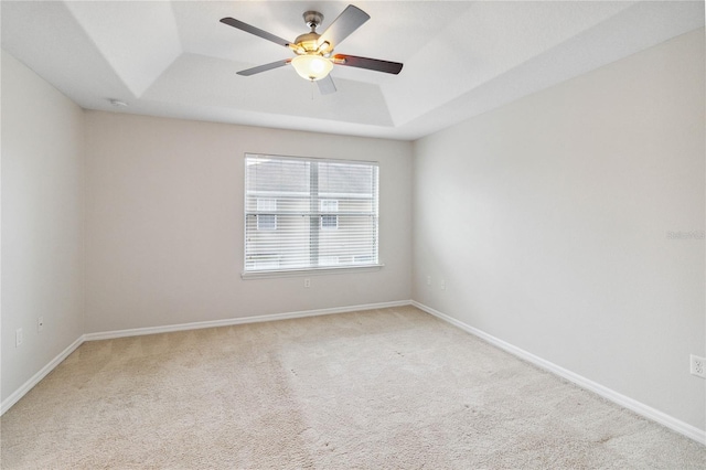 carpeted empty room featuring a raised ceiling and ceiling fan