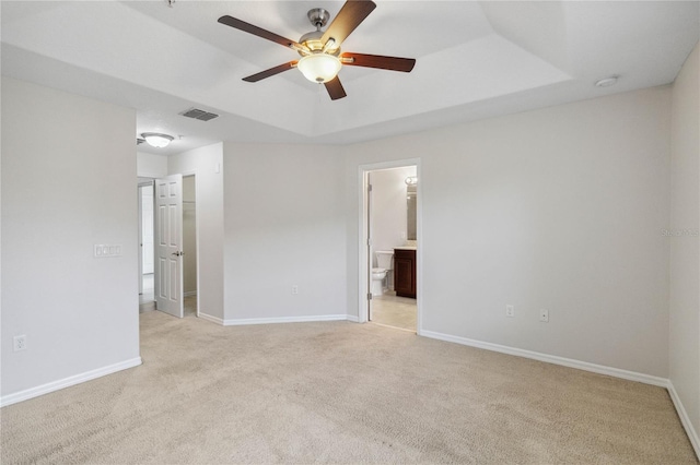 carpeted empty room featuring a tray ceiling and ceiling fan