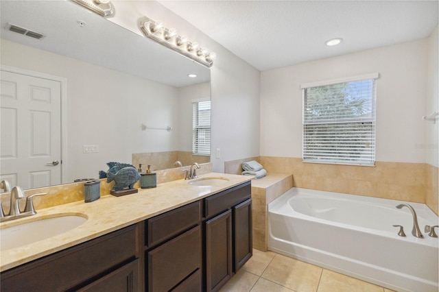 bathroom featuring vanity, a healthy amount of sunlight, tile patterned floors, and a tub to relax in