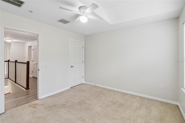 unfurnished room with ceiling fan, light carpet, and a textured ceiling