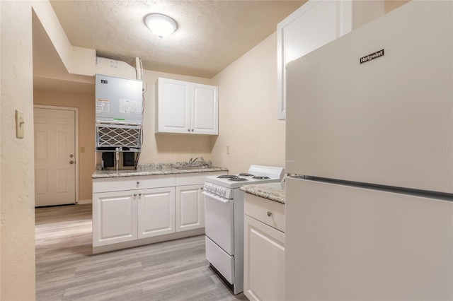 kitchen with light stone counters, white appliances, light hardwood / wood-style floors, and white cabinets