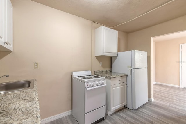 kitchen with sink, white cabinets, light stone counters, white appliances, and light hardwood / wood-style flooring