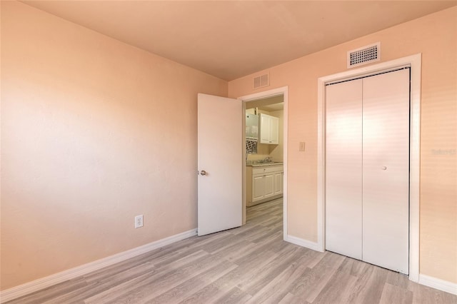 unfurnished bedroom with light hardwood / wood-style floors and a closet