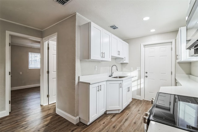 kitchen with hardwood / wood-style floors, white cabinetry, sink, electric stove, and crown molding