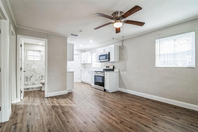 kitchen featuring a wealth of natural light, appliances with stainless steel finishes, dark hardwood / wood-style flooring, and white cabinets