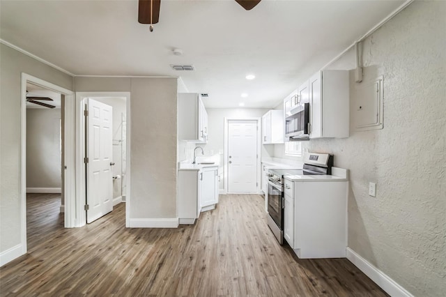 kitchen featuring wood-type flooring, sink, white cabinetry, and appliances with stainless steel finishes