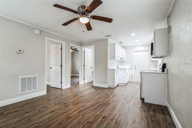 unfurnished living room featuring ceiling fan, crown molding, wood-type flooring, and sink