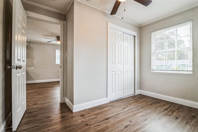 unfurnished bedroom featuring ceiling fan, a closet, dark hardwood / wood-style flooring, and crown molding