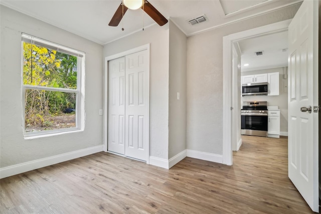 unfurnished bedroom with ceiling fan, a closet, light hardwood / wood-style flooring, and crown molding