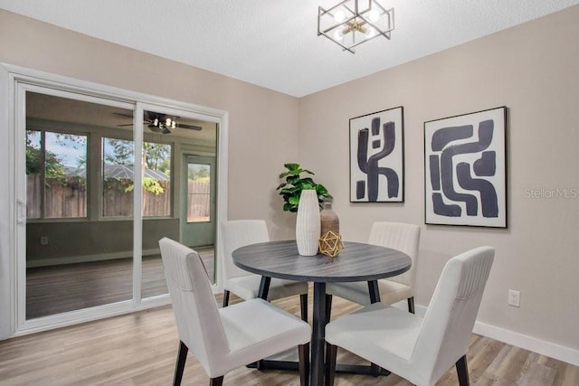 dining room with an inviting chandelier, a textured ceiling, and light hardwood / wood-style floors