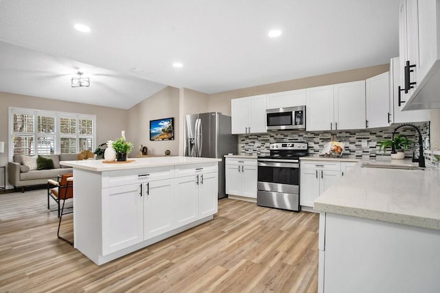 kitchen featuring sink, stainless steel appliances, tasteful backsplash, white cabinets, and vaulted ceiling