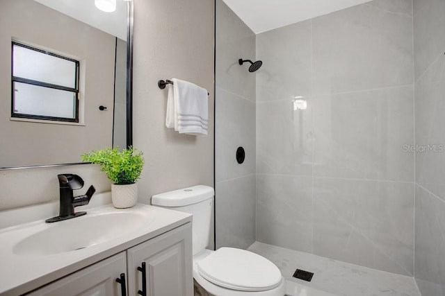 bathroom with vanity, toilet, and a tile shower