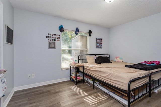 bedroom with multiple windows, a textured ceiling, and hardwood / wood-style floors