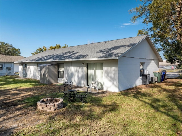 rear view of property featuring a lawn and a fire pit