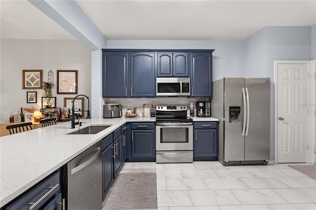 kitchen featuring stainless steel appliances, backsplash, blue cabinetry, and sink