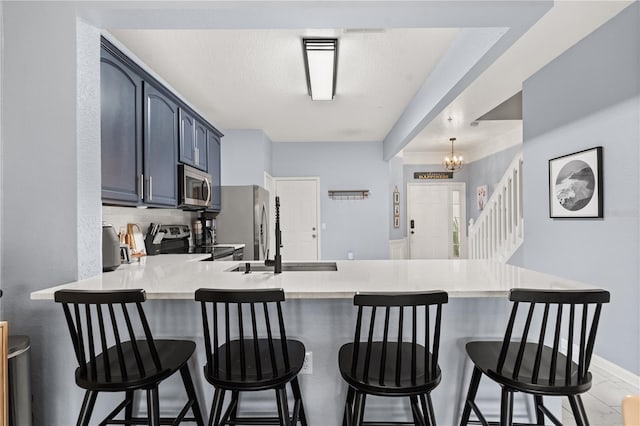 kitchen with a kitchen bar, kitchen peninsula, stainless steel appliances, a notable chandelier, and blue cabinets