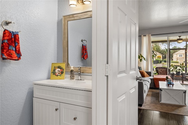 bathroom with a textured ceiling, wood-type flooring, and vanity