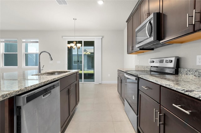 kitchen with appliances with stainless steel finishes, light stone countertops, sink, and hanging light fixtures